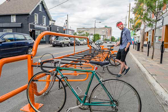 There’s no missing Kitchissippi’s new bike corrals. Hintonburg’s Chris Harlock locks up his bike. Photo by Ted Simpson.