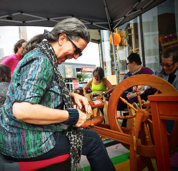 Outside Wabi-Sabi, local knitter Liane Thiry-Smith demonstrates proper wheel technique. They’re celebrating International Knitting Day. Not even the impending rain would stop these wool enthusiasts. 