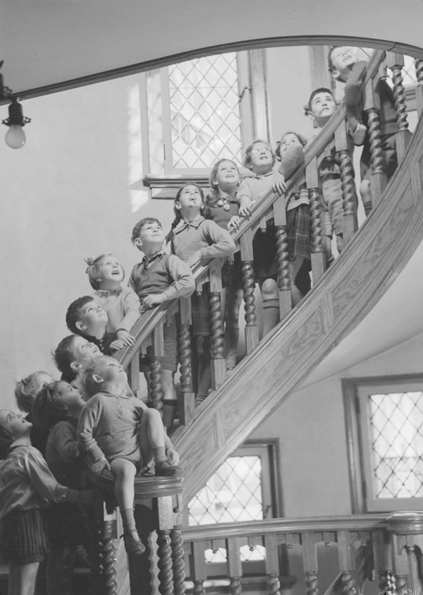 Many photo pose for a photo on a spiral staircase. It’s a black and white image. 