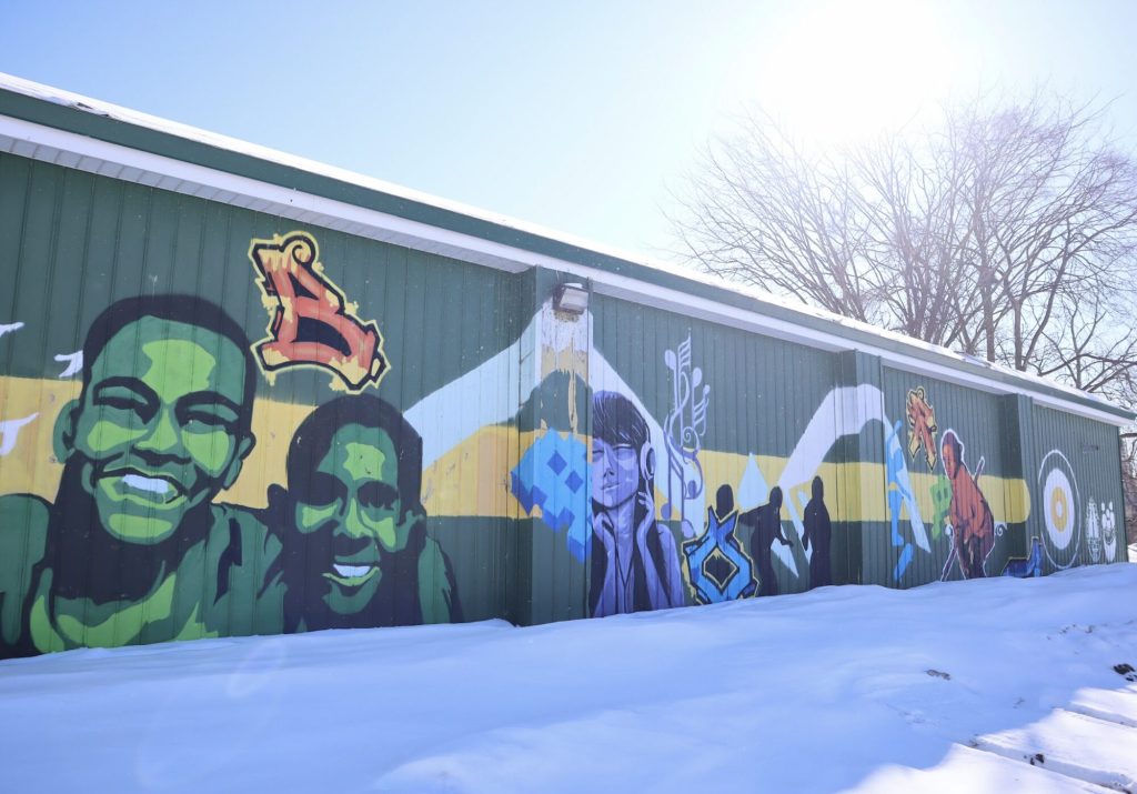 The exterior of the former Granite curling club with murals painted on it. 