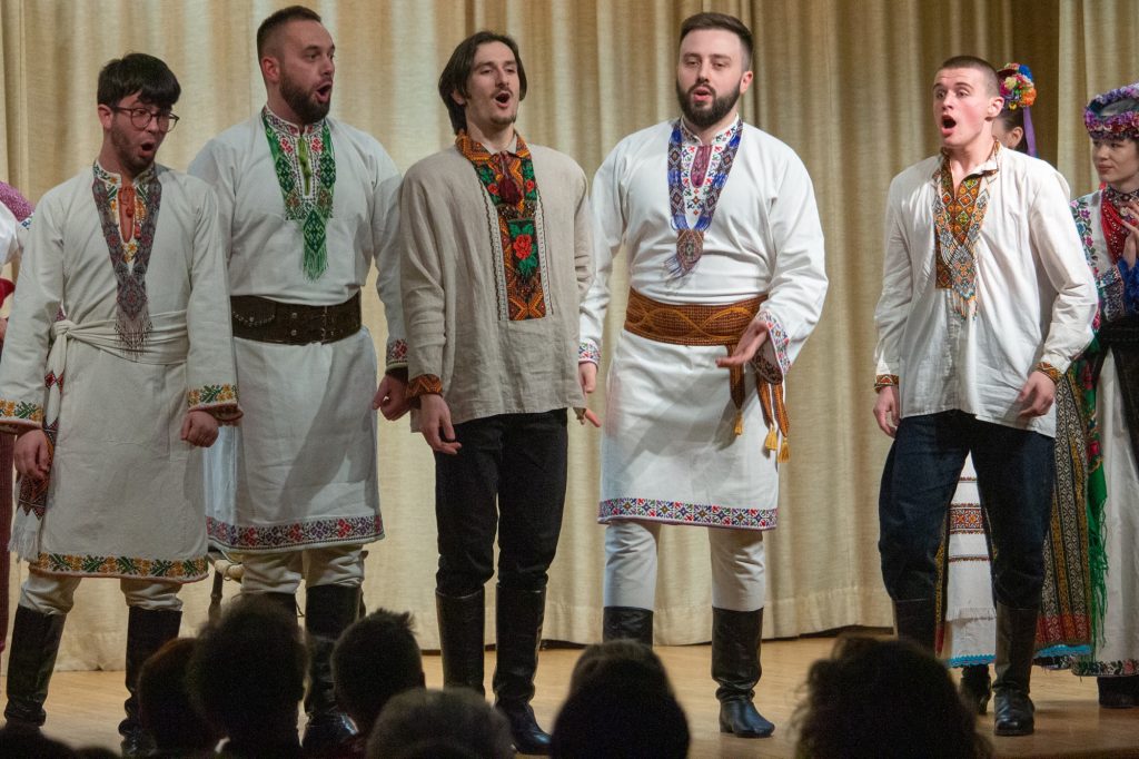 A group of five men singing passionately. 