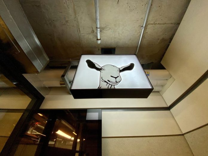 A Happy Goat Coffee sign hanging in an LRT station.|A black and red Happy Goat sign at an LRT station in Ottawa