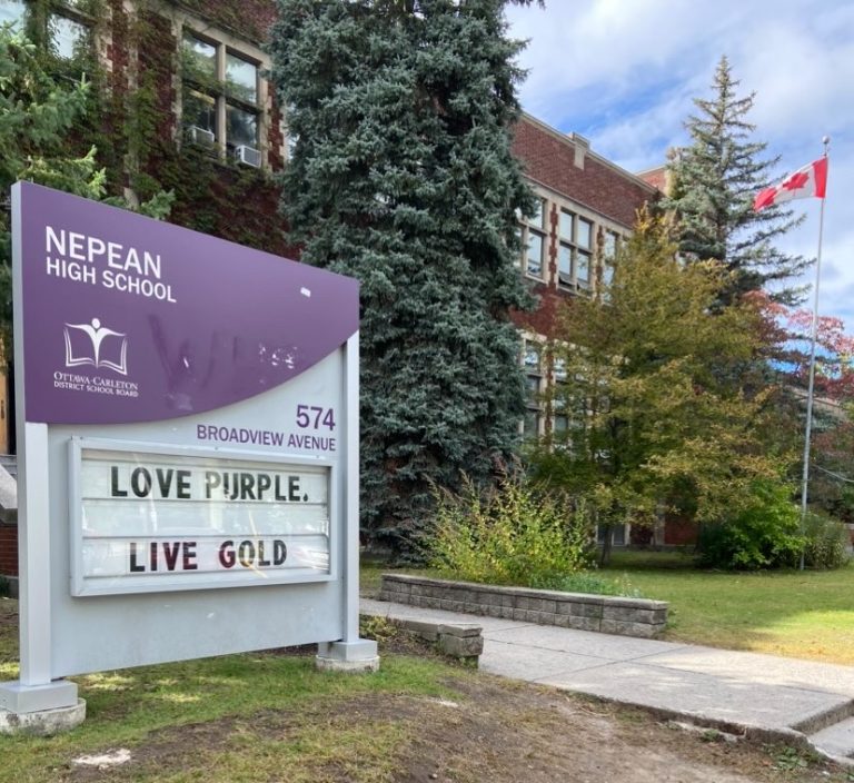 A purple and white sign outside on the lawn on Nepean High School. The sign reads "Love purple