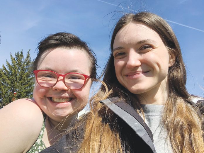 Two smiling girls take a photo of themselves outside on a sunny day.