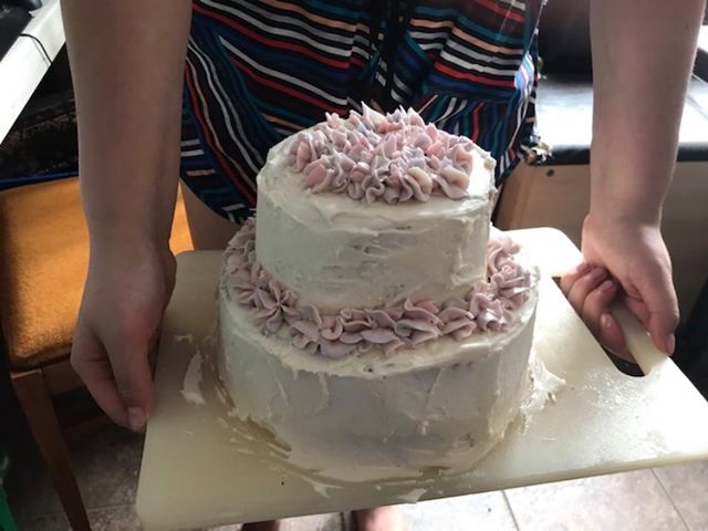 A photo of a white layer cake made by Isabelle Rose Golding during the COVID-19 pandemic.|A photo of Isabelle Golding holding a cake in Hintonburg this spring.