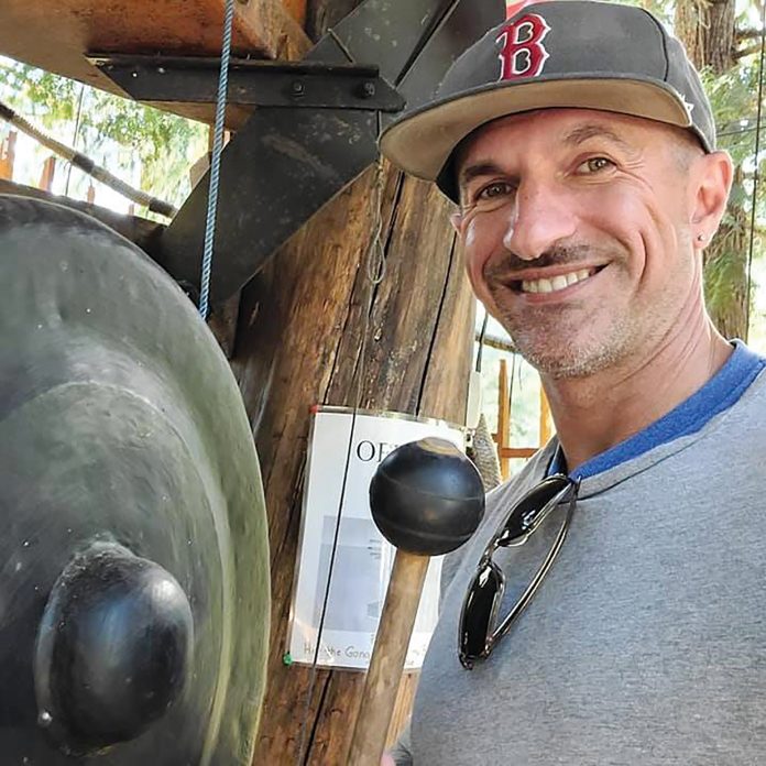 Jake Guay standing near a large grey gong