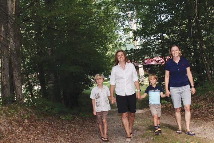 A photo of Vicky Marrack walking with her wife and two sons.