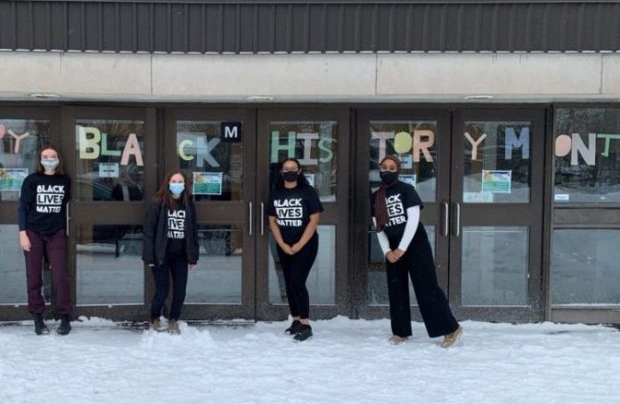 Four students stand outside of Nepean High School on a snow covered field wearing Black Lives Matter t-shirts for Black History Month