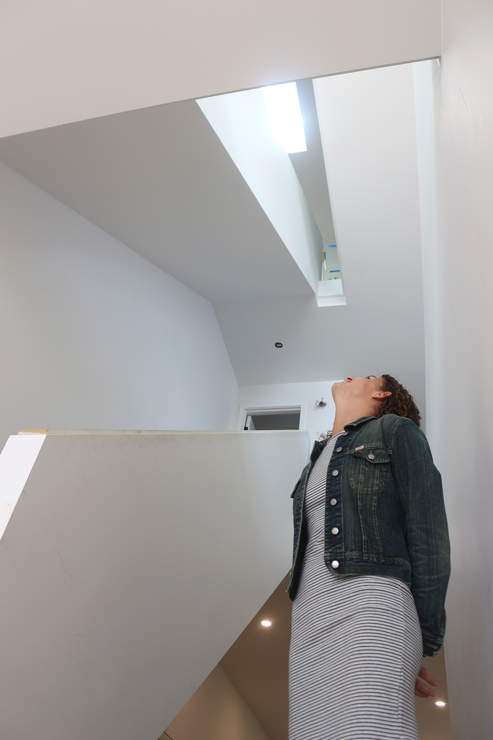 Aleta Moher stands at the bottom of the open stairwell, a feature that opens up the house and takes advantage of all the natural light the south-facing windows let in.