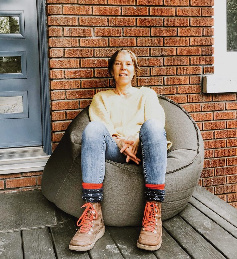 Tina Le Moine sitting in a bean bag chair in front of her brick house.