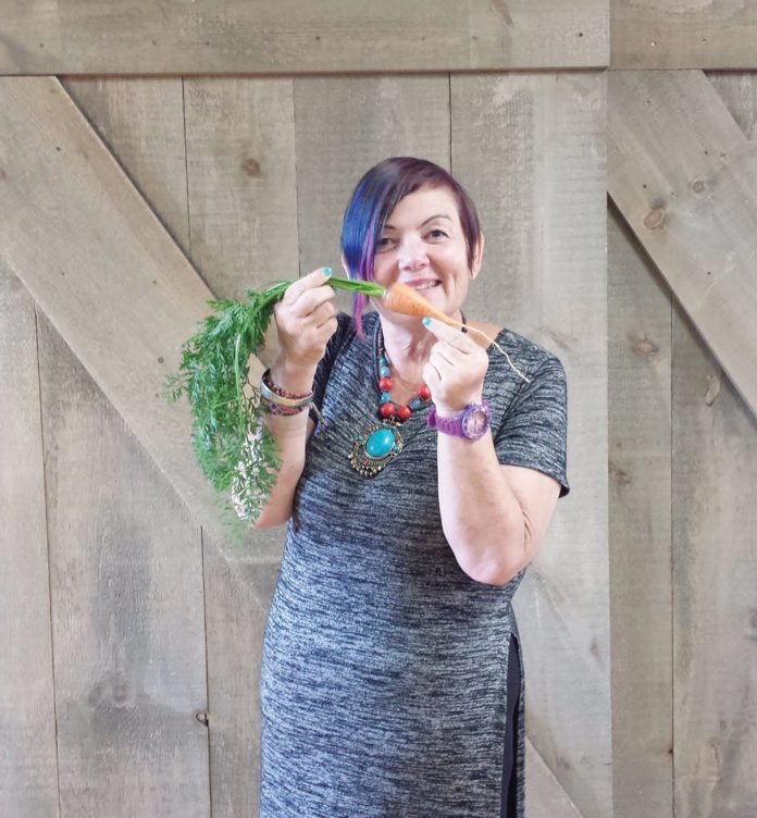 Karen Secord holding a carrot at Parkdale Food Centre.