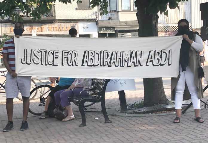 Two organizers holding a banner at 55 Hilda St. on the fourth anniversary of Abdi's death in July 2020.|||||