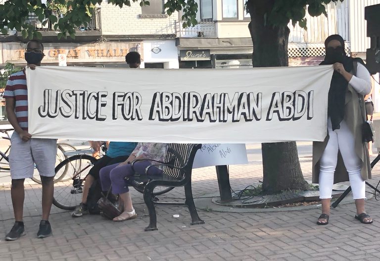 Two organizers holding a banner at 55 Hilda St. on the fourth anniversary of Abdi's death in July 2020.|||||