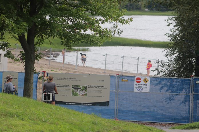 A wide shot of Westboro Beach closed off for construction with water in the background. In the foreground