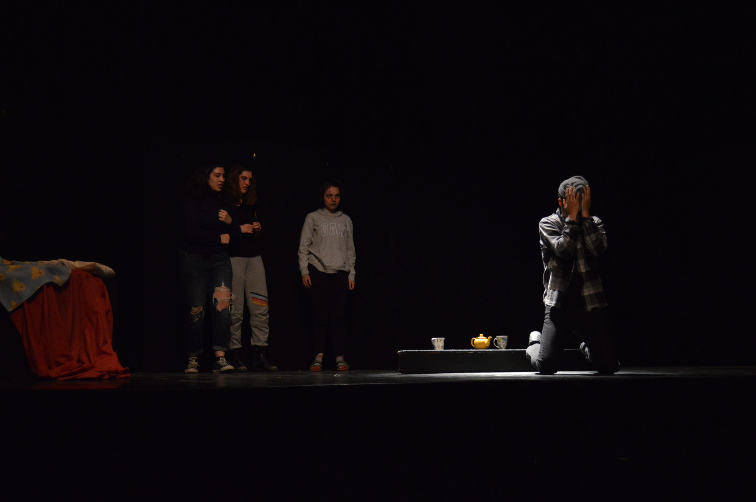 Braeden Moore (center) crouches in despair as Jada Badawy (left), Anna Carsley-Jones (middle) and Katie Laperle (right) watch on during the performance of the student-led play State of Mind.