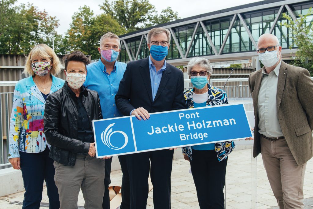 A photo of the mayor, former mayor and current councillors outside of Jackie Holzman Bridge in Ottawa.