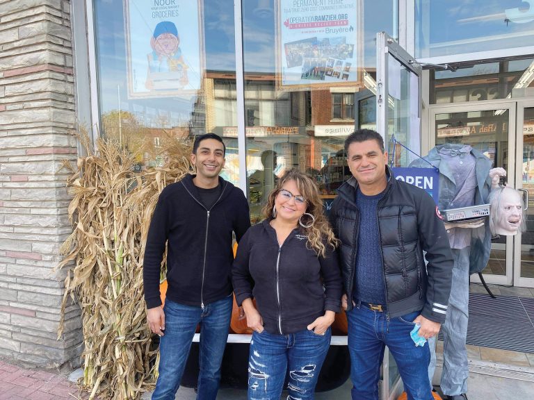 A photo of the three managers and owners of Noor Food Market outside their store in fall.|