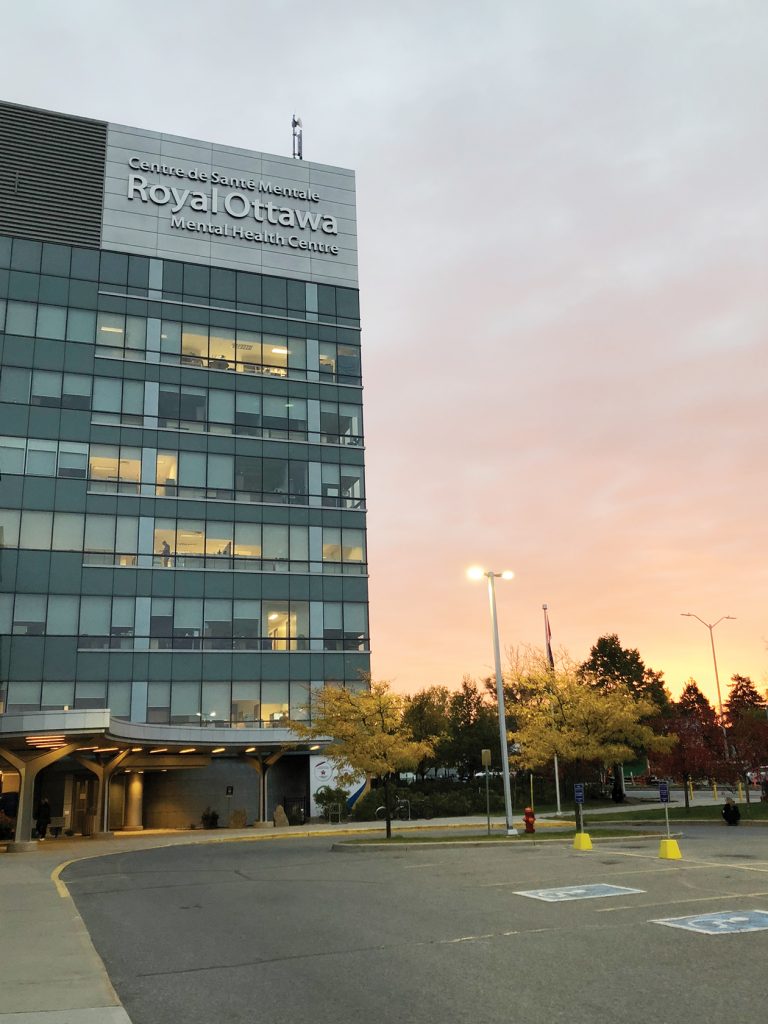 A tall shot of the Royal Mental Health Centre outside at sunset|A headshot of Dr. Raj Bhatla against a white background|A headshot of Dr. Florence Dzierszinski against a white background