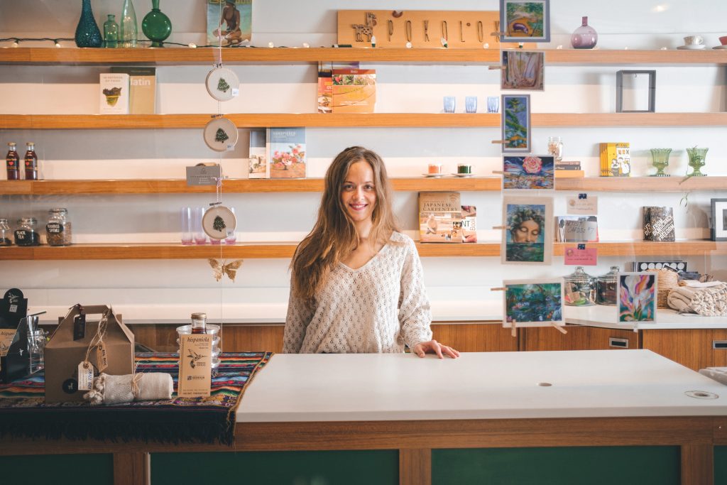 Jessie Lyon stands in front of shelves at at the cash register in Pokoloko X Cloud Forest.