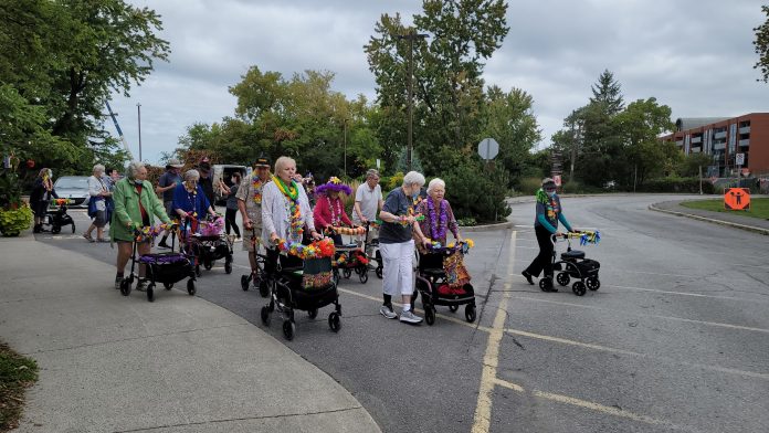 A group photo of seniors walking in a parade fundraiser event outside of Unitarian House.