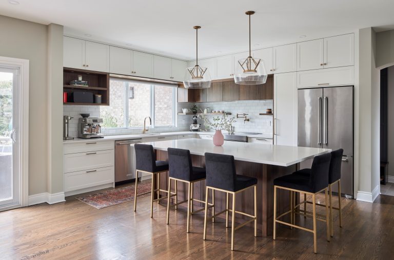 A professional photo of a recently renovated kitchen. There are white appliances and white countertops and black chairs.|A photo of a kitchen with many things on the counters. The kitchen is black and white.