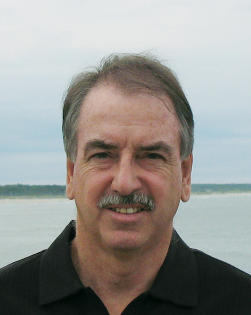 A headshot of Brian Harrison against the backdrop of a river on an overcast day