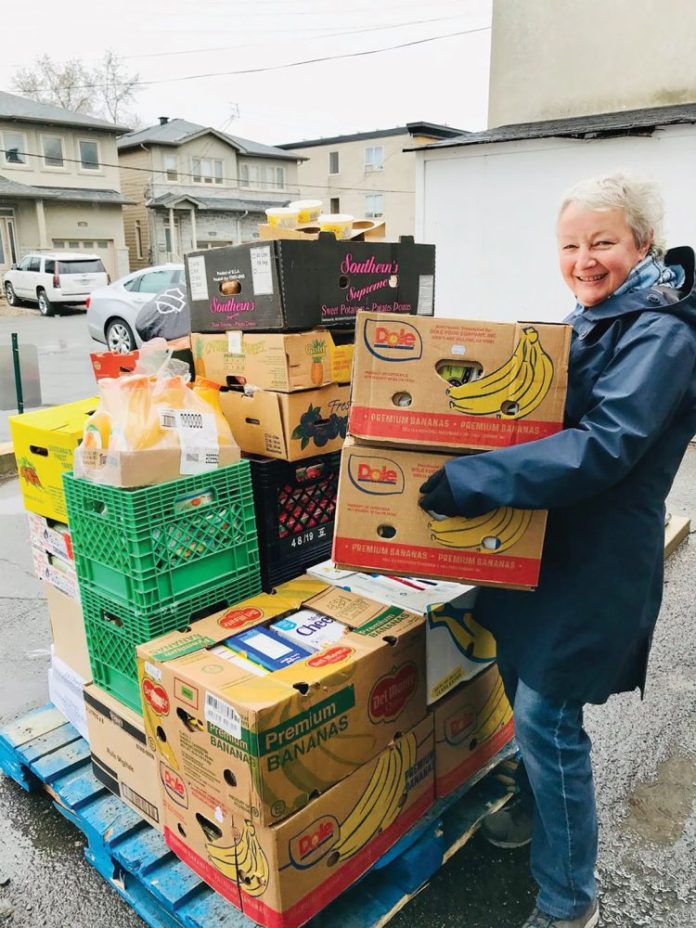 A photo of a volunteer at the Westboro Region Food Bank carrying boxes of food.|A photo of the food bank volunteers outside in Westboro in front of a food delivery truck