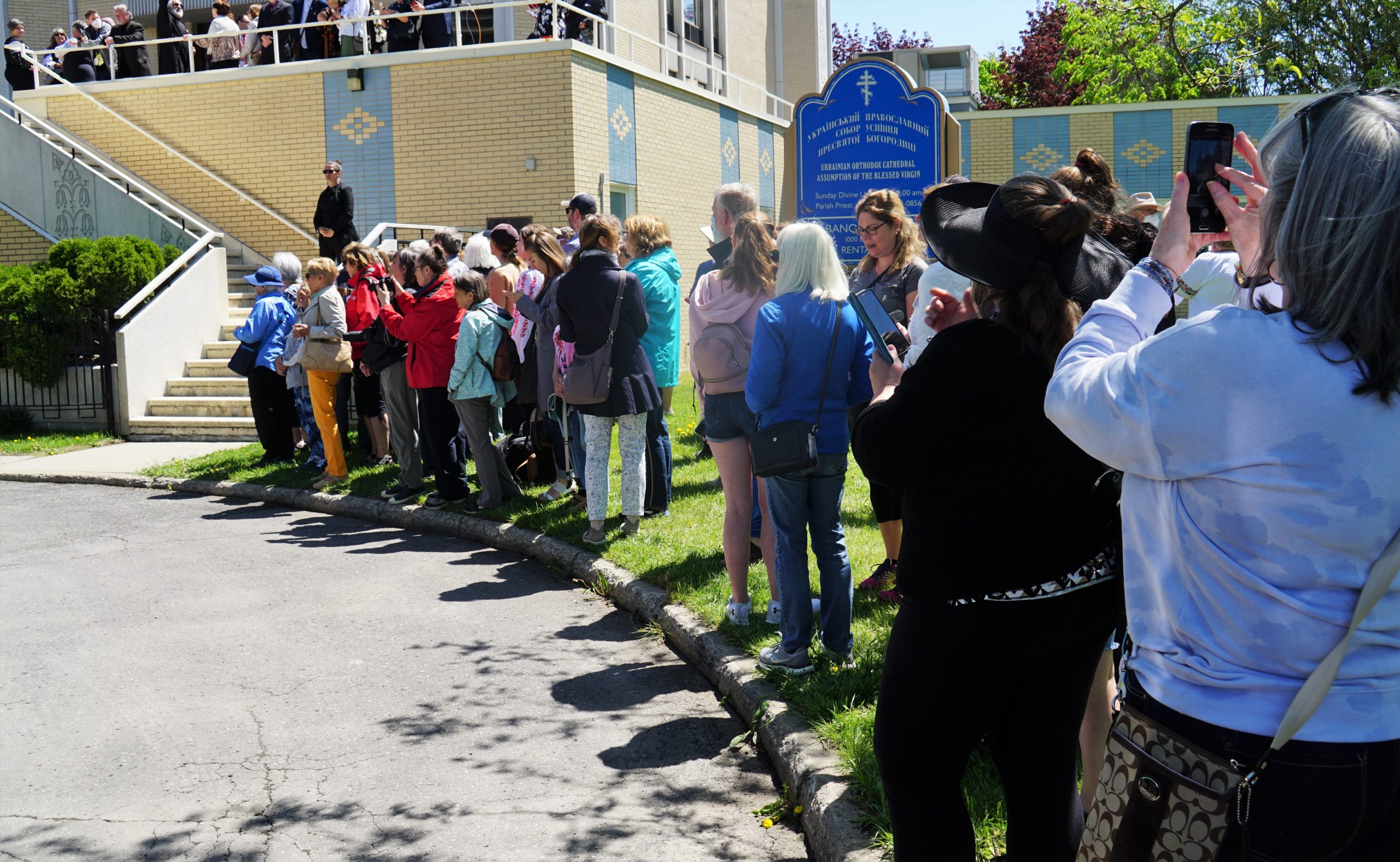 A row of people stand outside the Ukrainian Cathedral hall waiting for the royals to leave the building.