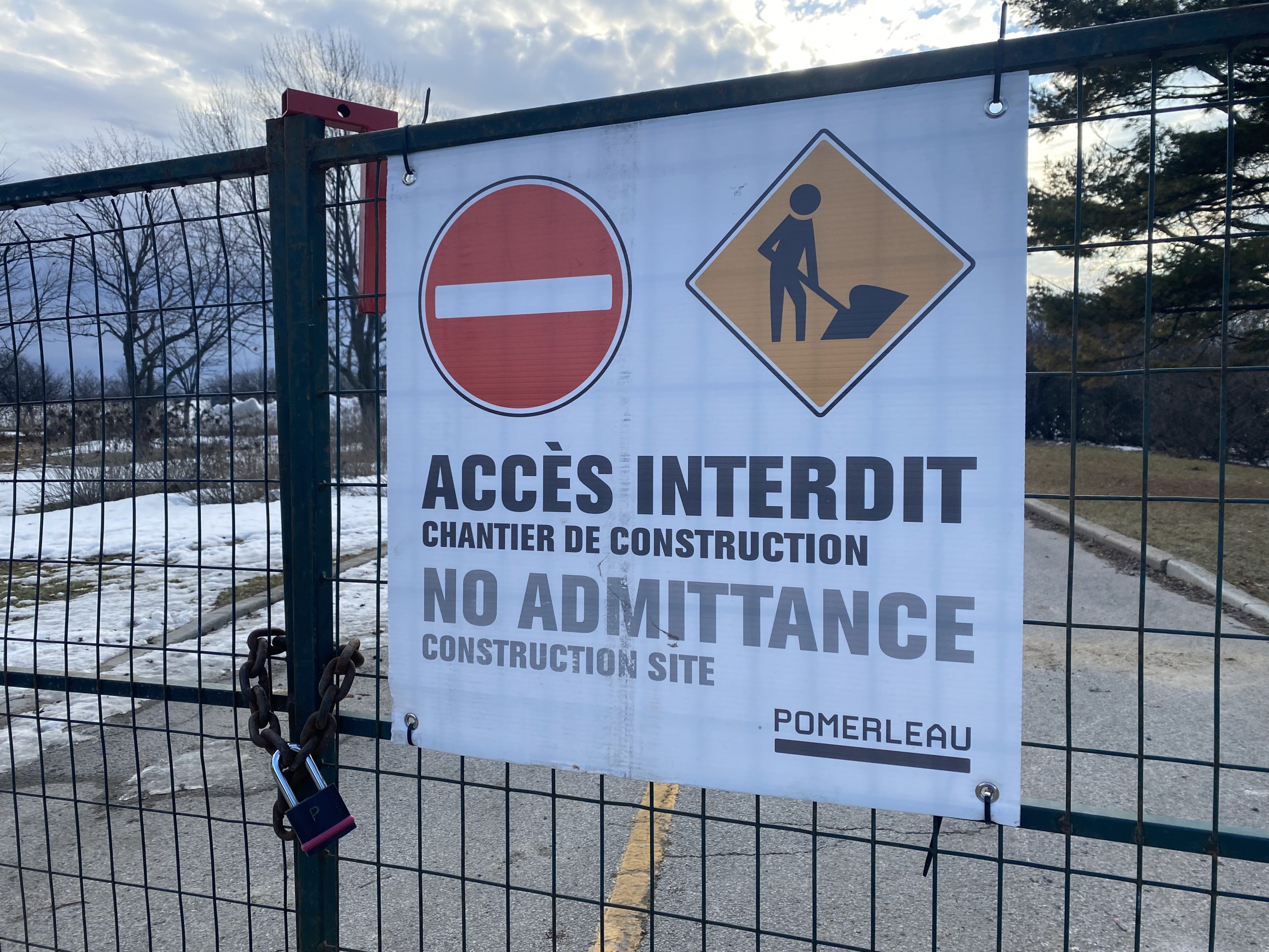 A close up of a white "no admittance" sign at Westboro Beach with a road and snow in the background.