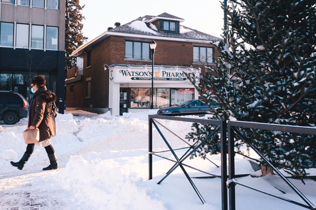 Watson's Pharmacy is seen across a snow covered Wellington West Street. A woman walks with a brown paper bag on the left.|||