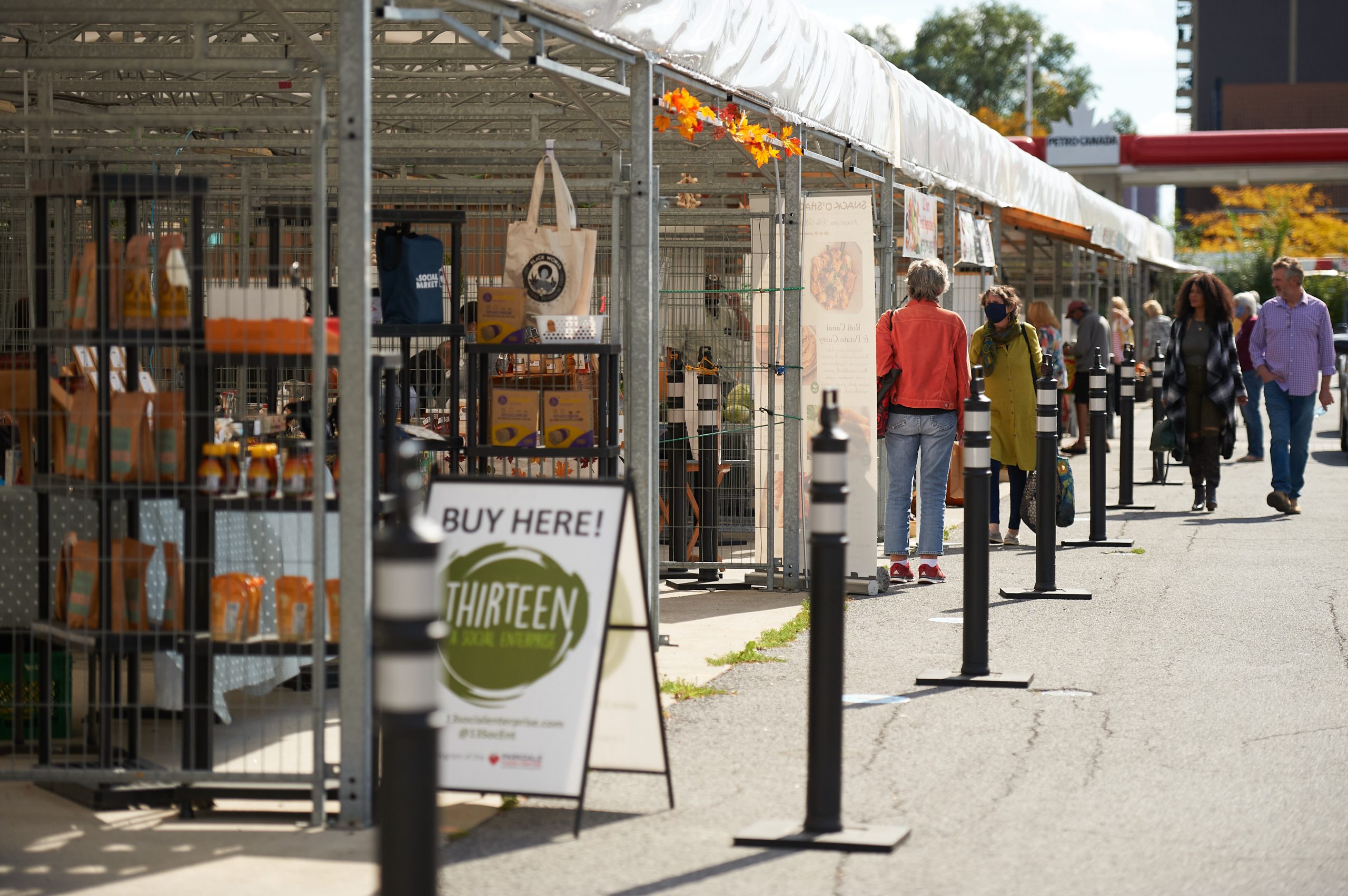 The side of the Parkdale Market on a sunny day in fall with signs and vendors out