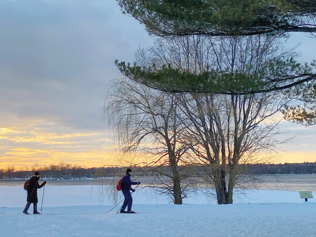 Two skiiers on the SJAM trail at sunset