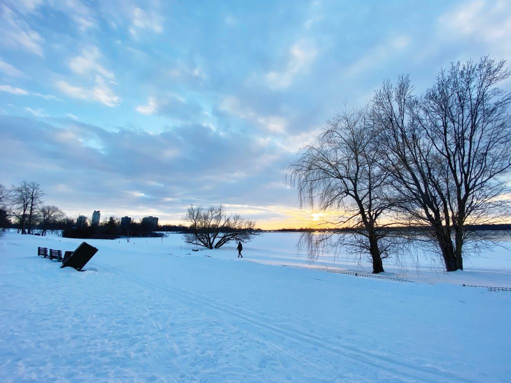 A snow covered field and the Ottawa River are seen at sunset.