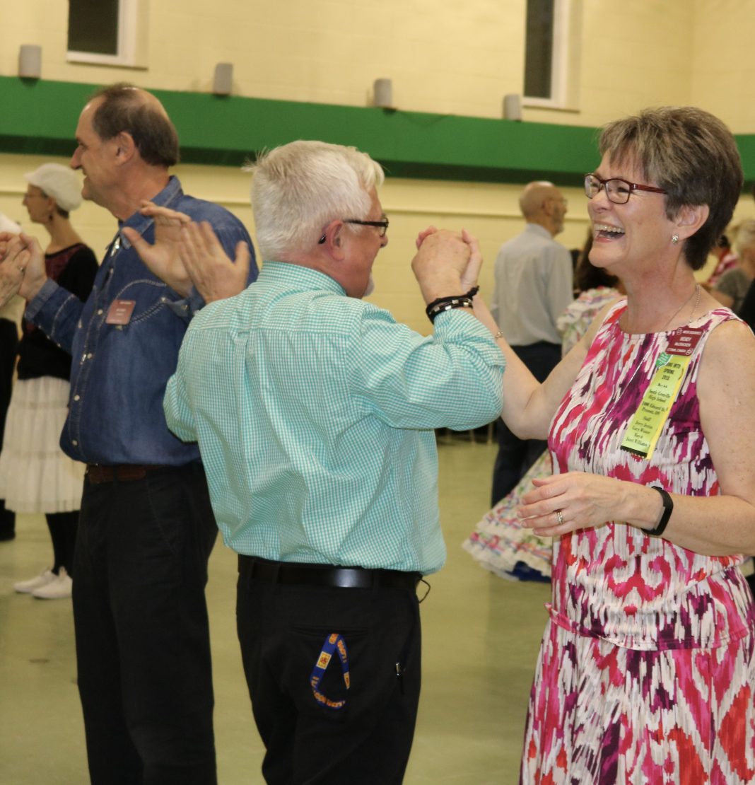 Two seniors do a square dance in a school gymnasium.|