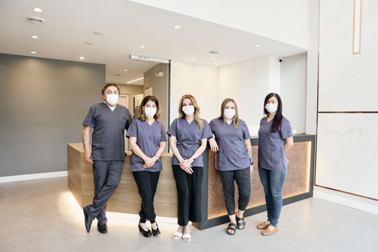 The team at W Dental Studio is seen wearing scrubs and masks standing in a line in the main lobby|