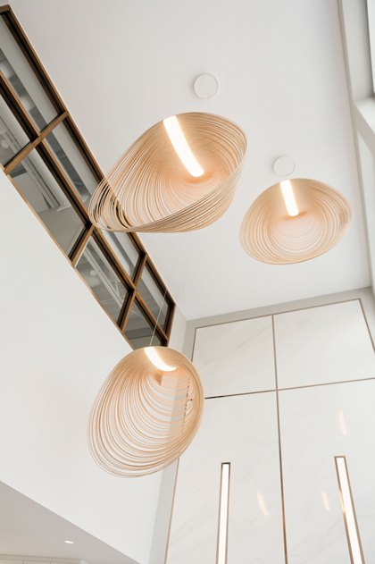 Three shell-shaped lights are seen hanging in a bright white lobby at W Dental Studio