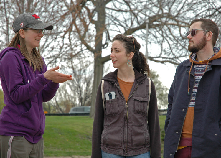 Erin explains to onlookers, Beck Langstone and Ryan Geikie, that the wheels on Bowie the beach cleaning bot, is the best design she has tested thus far.