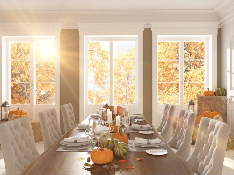 A living room table with pumpkins on it and light streaming through the window|