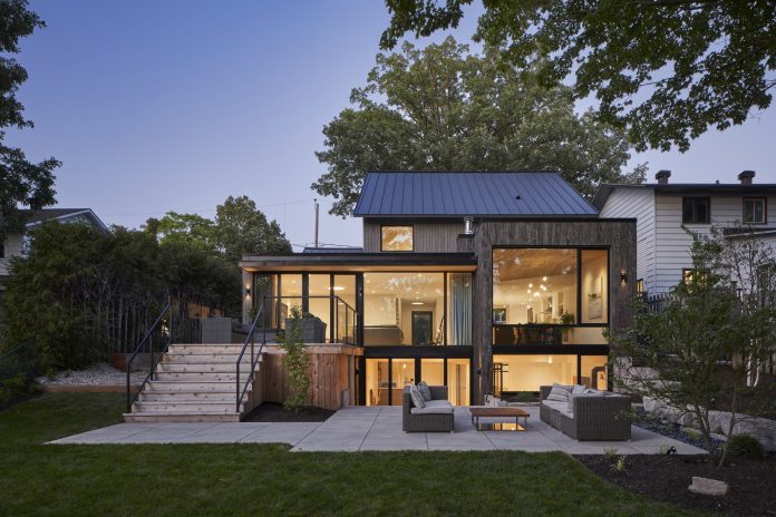 The outside of a back of a three story house in Kitchissippi with wide open windows and leading out to a patio with grass|||