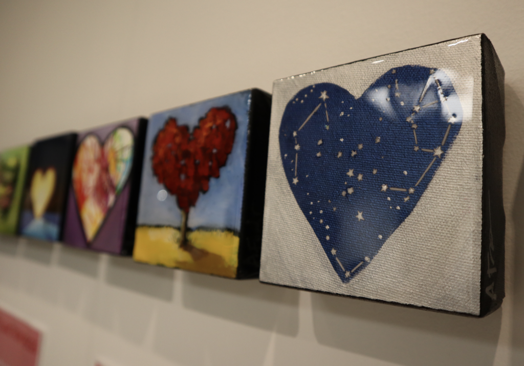 A number of Alison’s hearts are in a row on a wall. The first is a blue heart with stars.