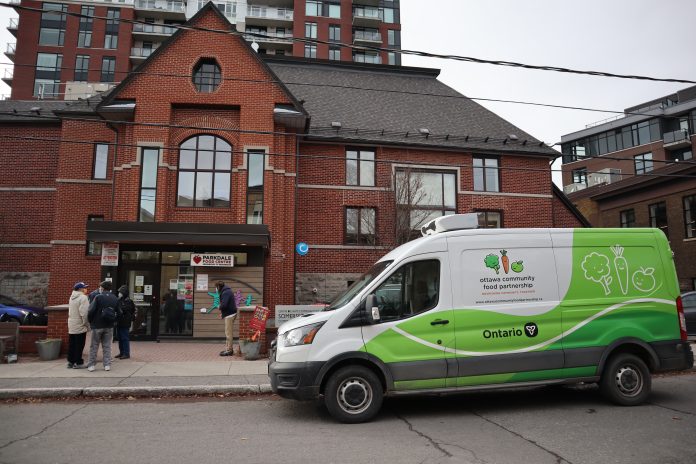 The exterior of the Parkdale Food Centre. A truck is parked outside and people are mingling by the door