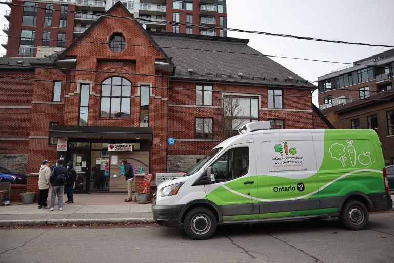 The exterior of the Parkdale Food Centre. A truck is parked outside and people are mingling by the door