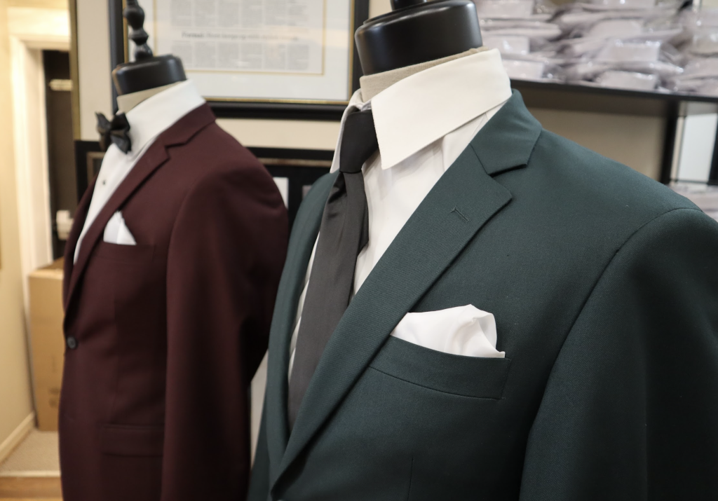 A burgundy and dark green suit sit on racks at Morris formalware.