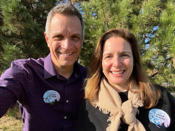 A man and woman take a selfie on a sunny day. They are wearing “I voted” stickers|A man holds a microphone after being elected as Ottawa’s next Mayor.|