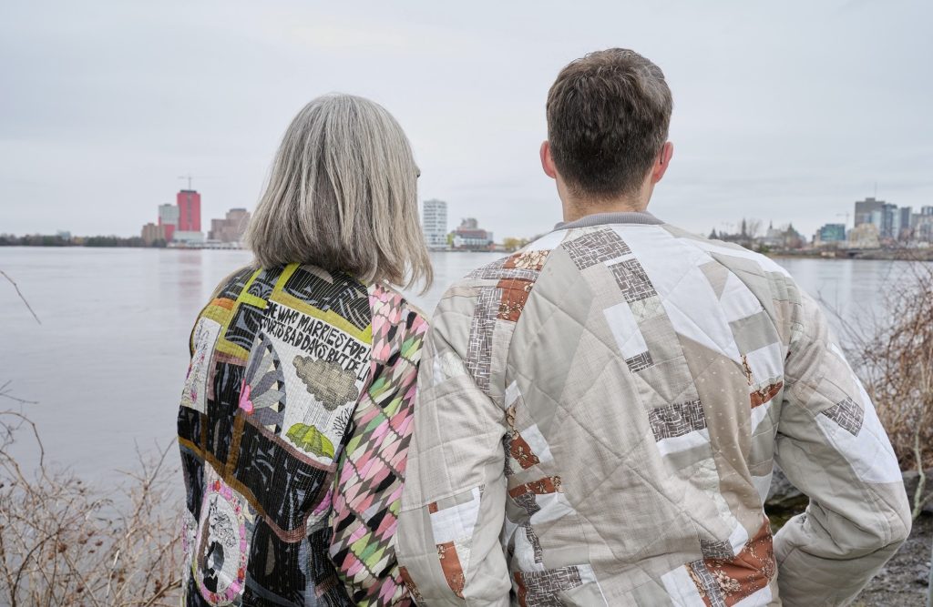 Kristen and Joel look over the Ottawa river with their backs turned facing the Quebec side. 