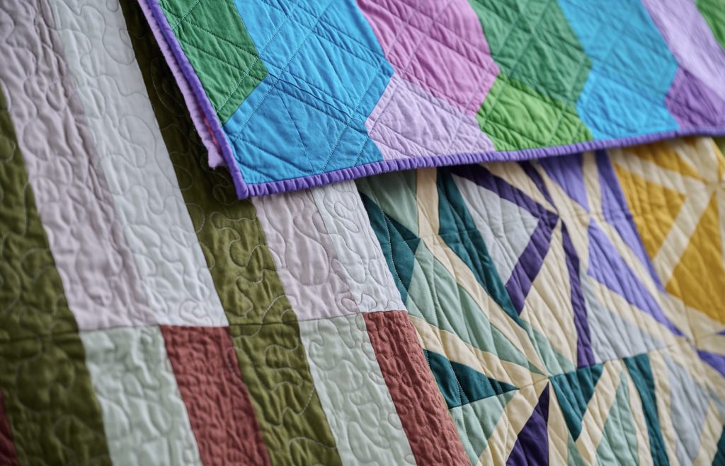 An up close photo of three colourful quilts. 