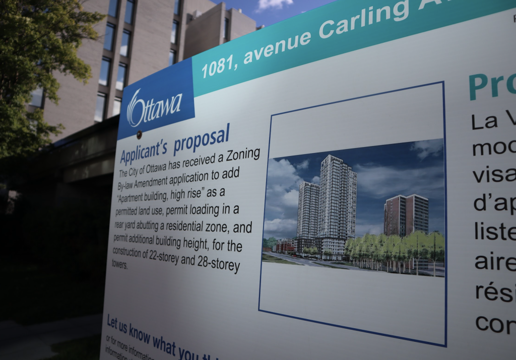 A sign stating plans for the new development sits outside of 1081 Carling.