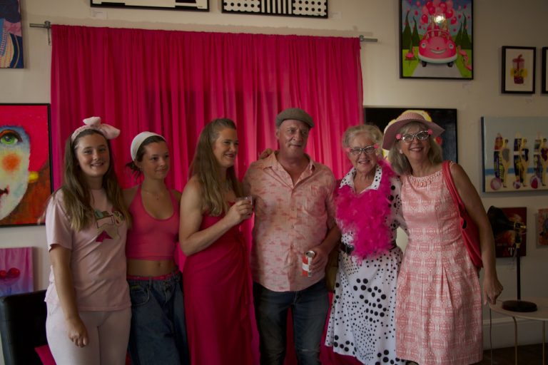 Six people wearing pink pose for a photograph.