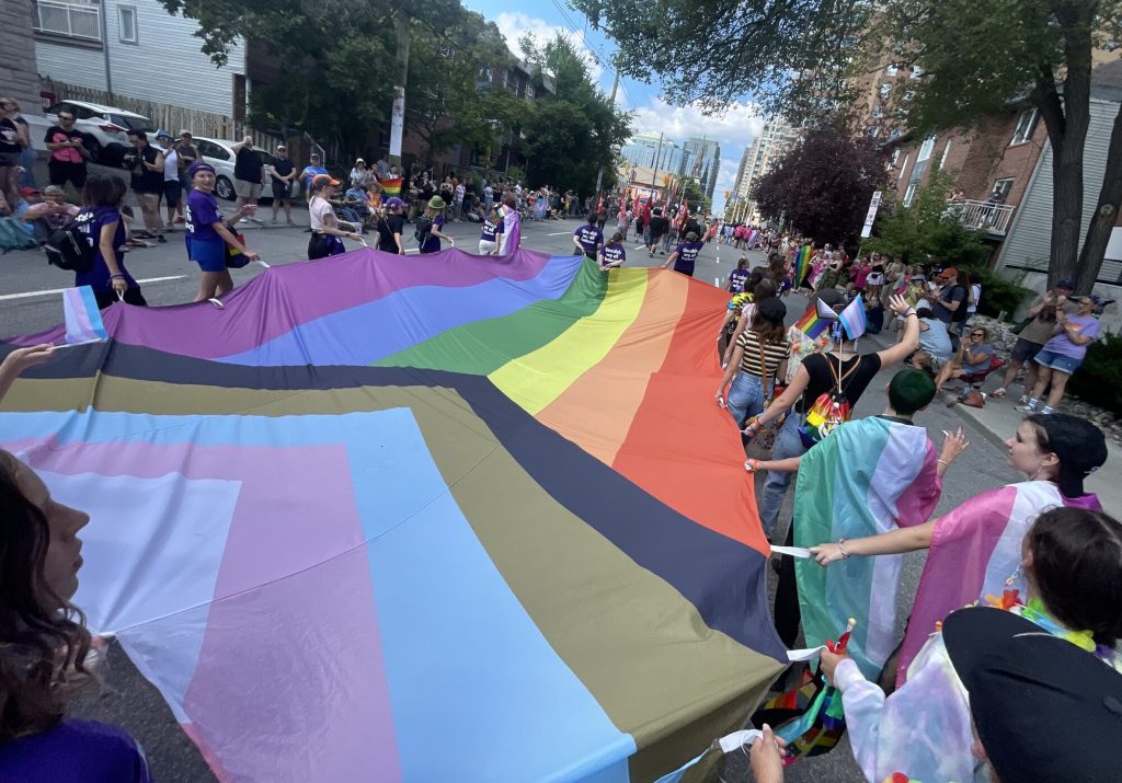 A progress pride flag is carried through the streets of downtown Ottawa. 