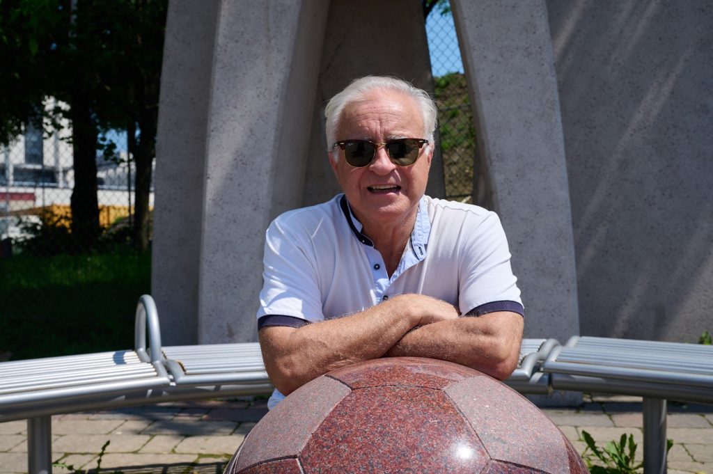 Tony leans on a sculpture of a soccer ball.  